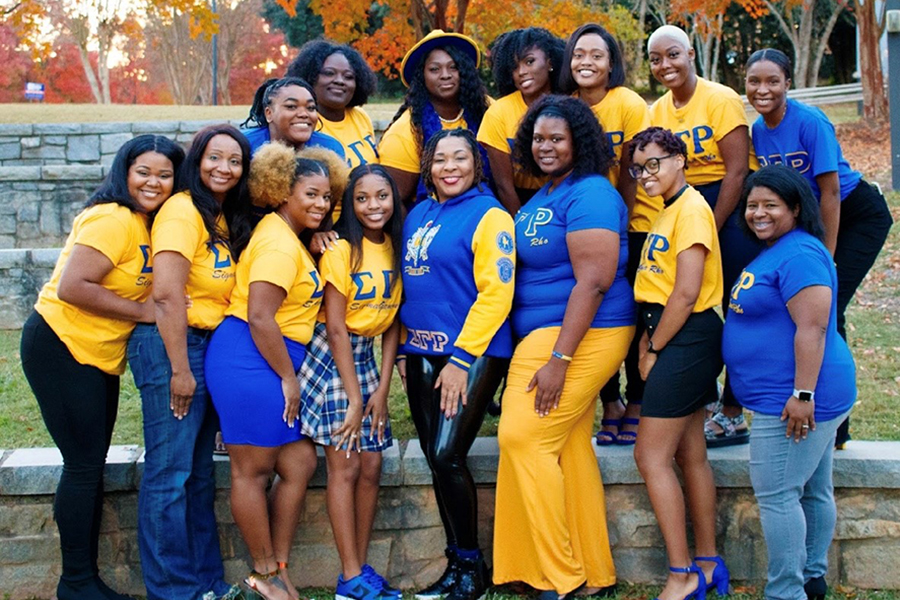 Members of Rho Lambda Chapter of Sigma Gamma Rho standing at the amphitheater wearing blue and gold Greek Letter paraphenalia