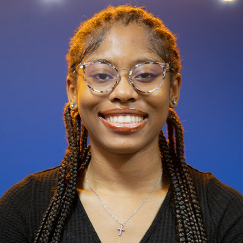 Image of Amaya Marie Myers, where a black cardigan and black-and-white framed glasses
