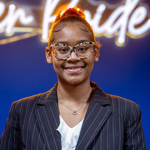 Image of Morgan Scott wearing a white blouse under a navy pin-striped jacket