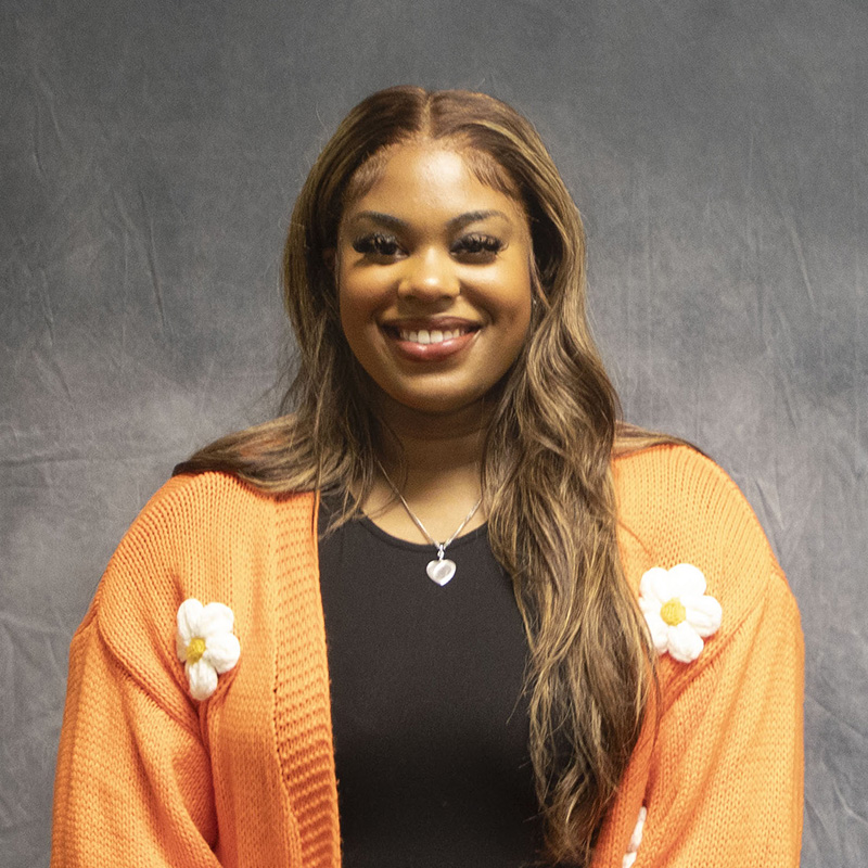 Image of Lamaya Nelson wearing a peach cardigan with white flowers and a black shirt