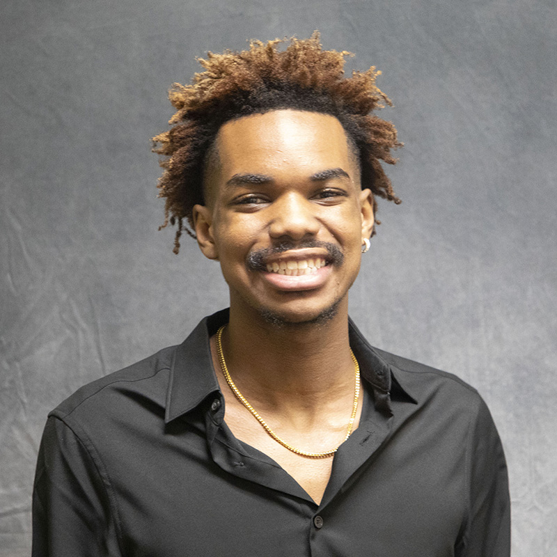 Image of Nehemiah Horton wearing a black button-up shirt and a gold rope chain.