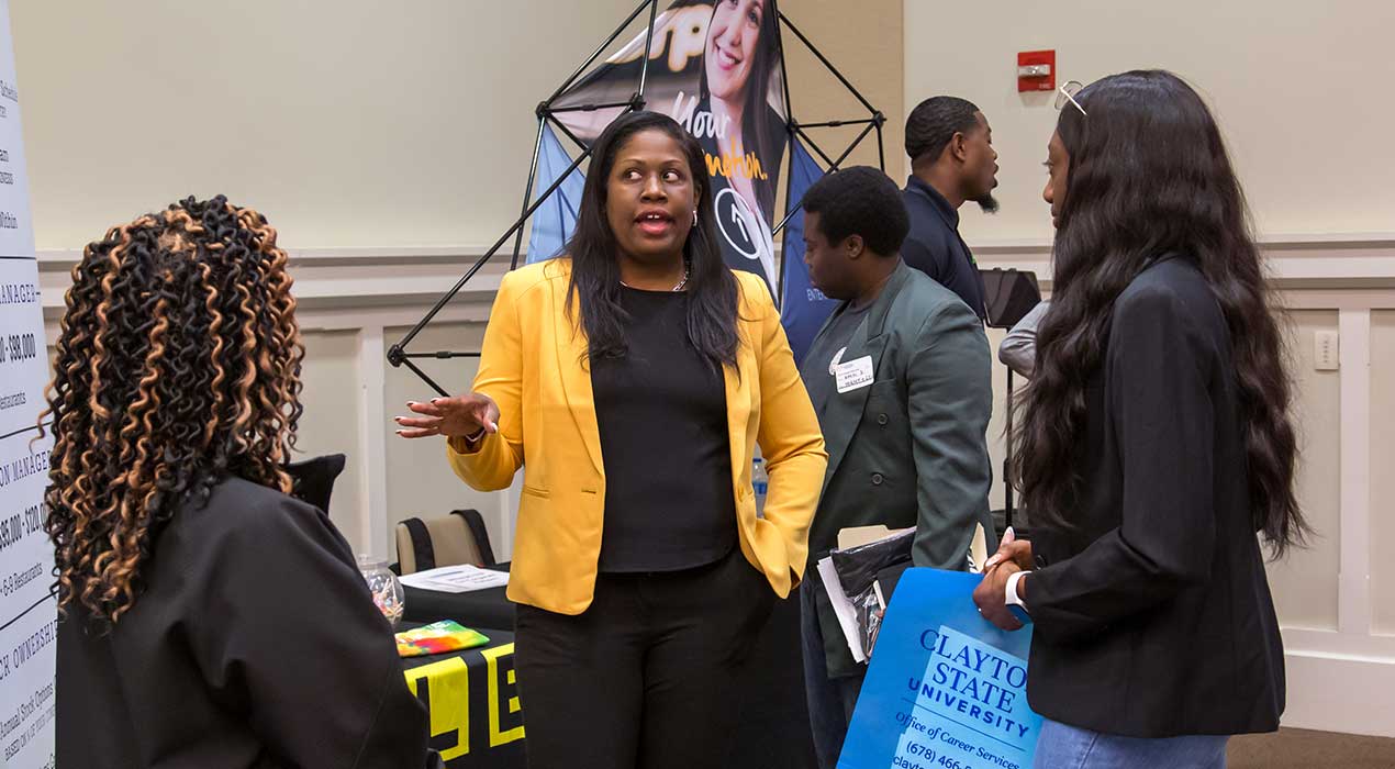 Students engage with a representative from Waffle House at the 2024 Jobs & Graduate School Fair