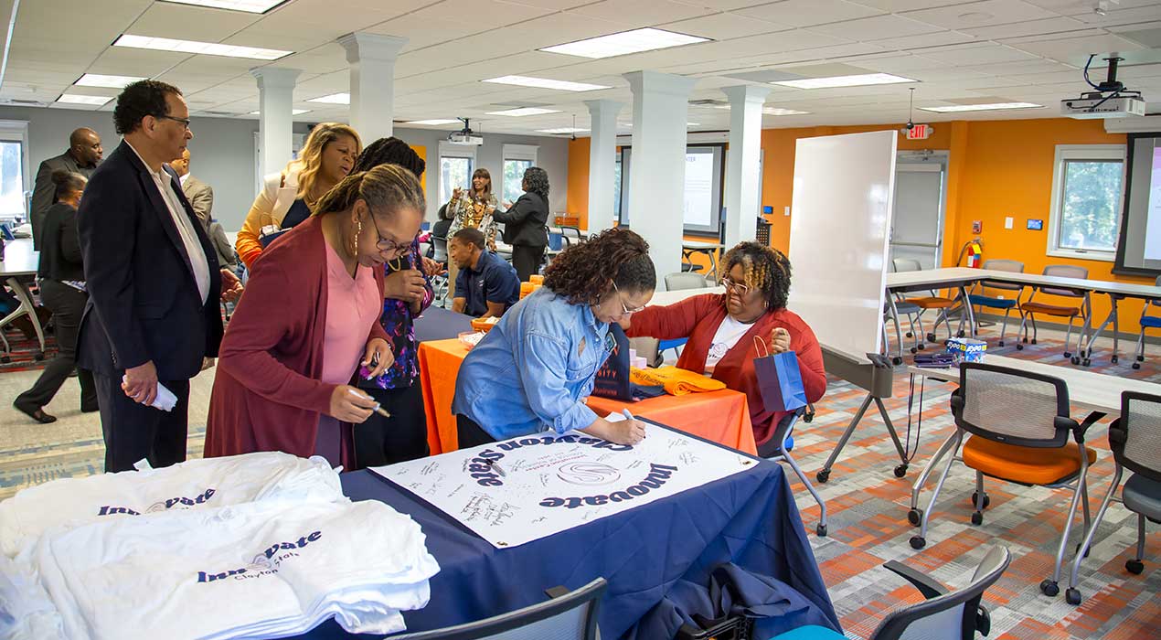 Students, staff sign a grand opening sign at the newly opened College of Business Innovation Center